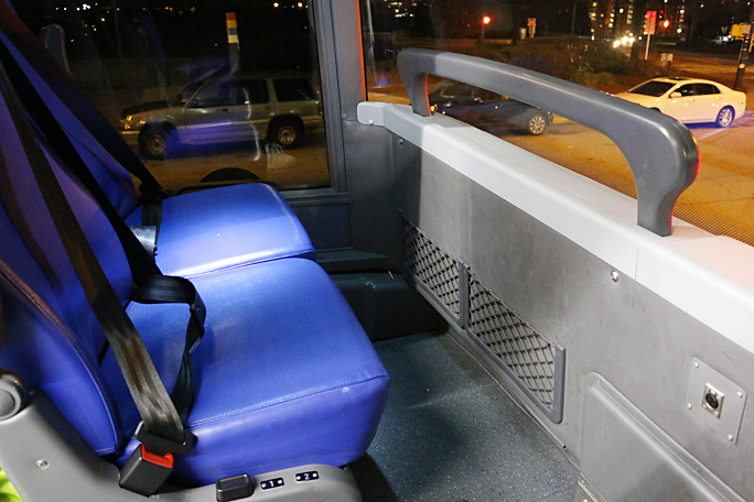 These are the two seats across the aisle from mine on the upper deck of a Megabus. Although a “cut-out” is provided for feet, there is not much legroom. The black button on the side allows the seat to be reclined. Note the ample amount of viewing room thanks to the abundance of windows. Photograph ©2015 by Brian Cohen.